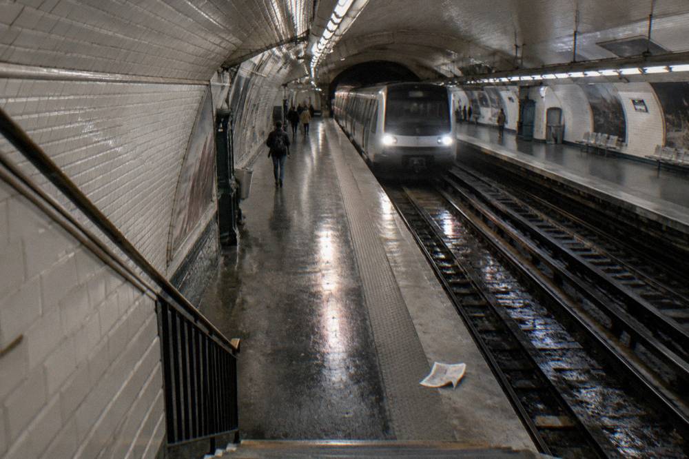 A Paris metro platform with a train arriving and signage above the tracks