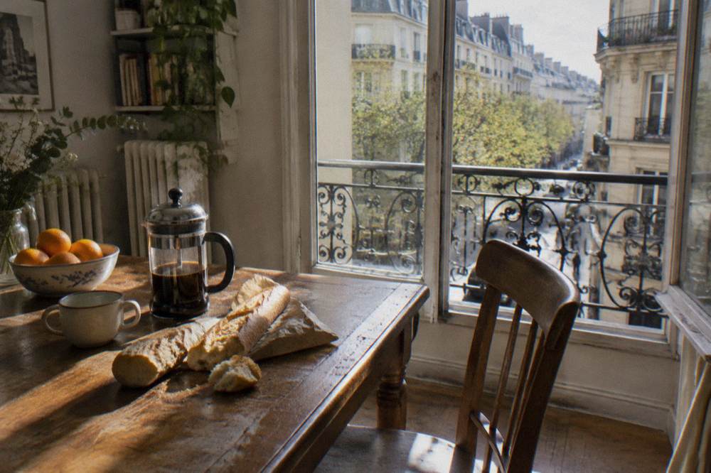 A table set with a simple breakfast of bread, coffee and fruit inside a Paris apartment