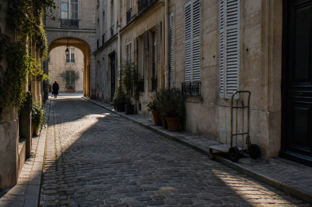 Cobblestone lane in an old Paris quarter with tall shuttered buildings