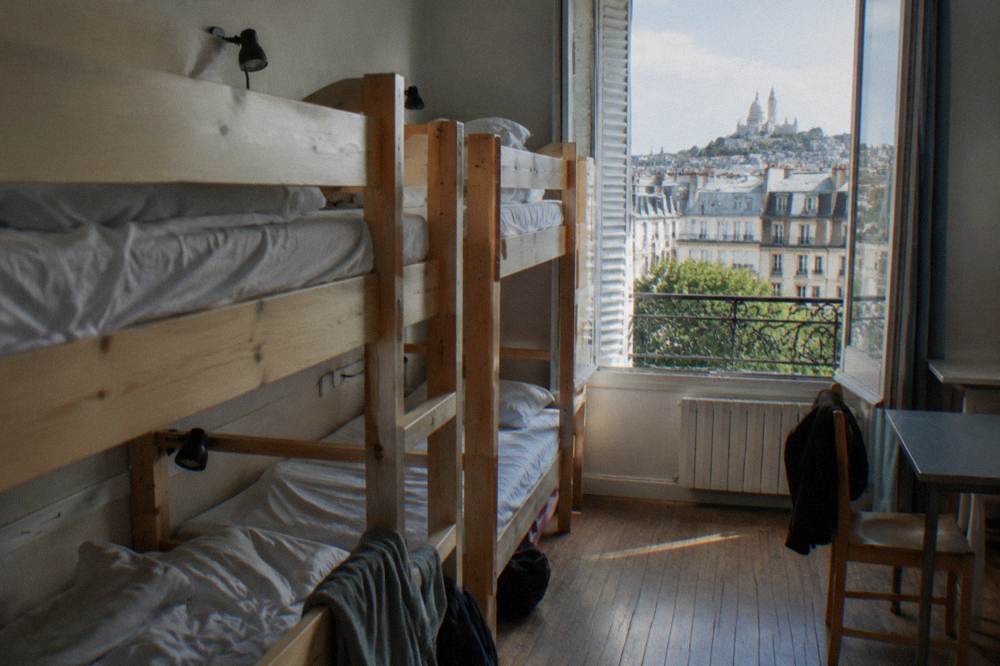 Bunk beds in a bright hostel dorm room with personal reading lights