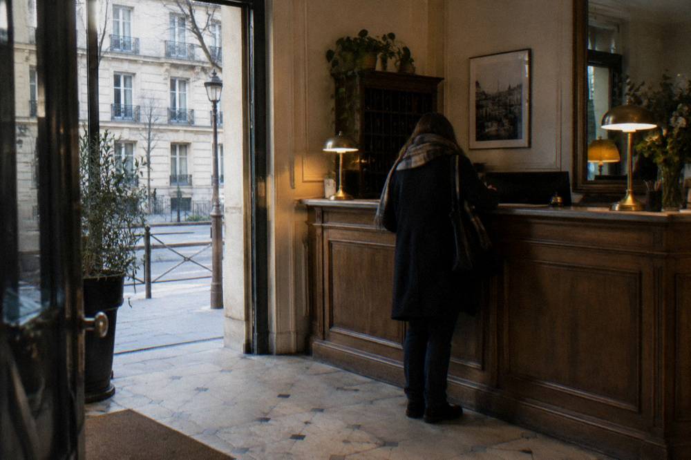 A hotel reception desk in Paris with a guest registering at the counter