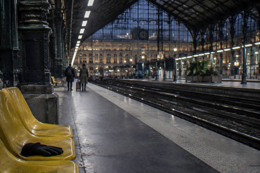 An RER platform in Paris at night with a lit station sign and waiting passengers