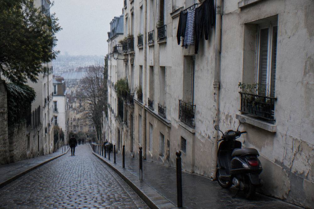 A narrow Paris street with old apartment buildings and a bicycle leaning against a wall