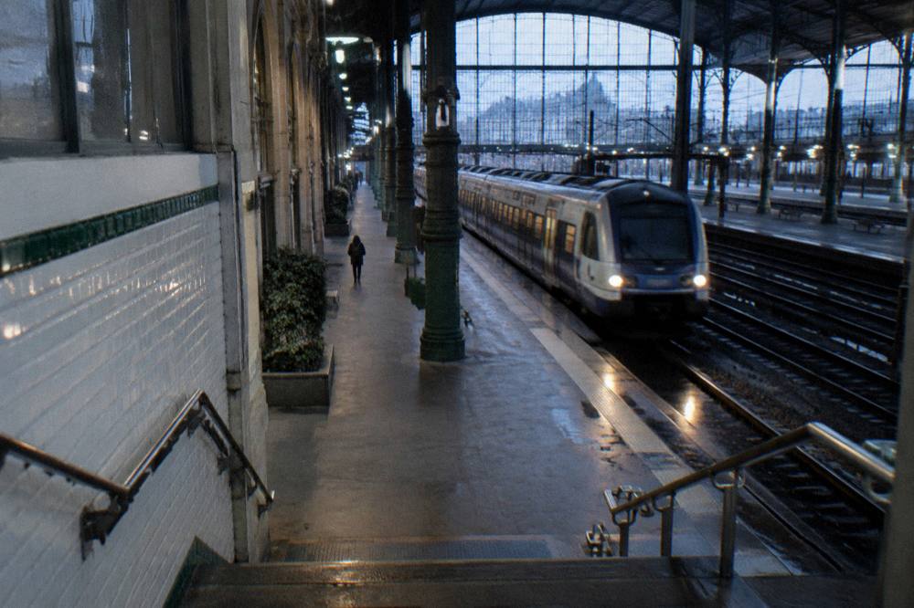 A Paris metro station platform with a train arriving and tiled walls
